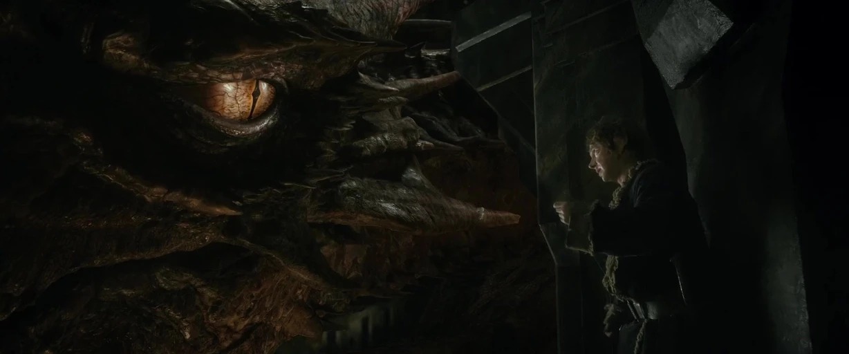 A massive, scaled dragon head with a glowing eye looms over a tiny humanoid figure. They are situated within a vast, dark, rocky subterranean space.