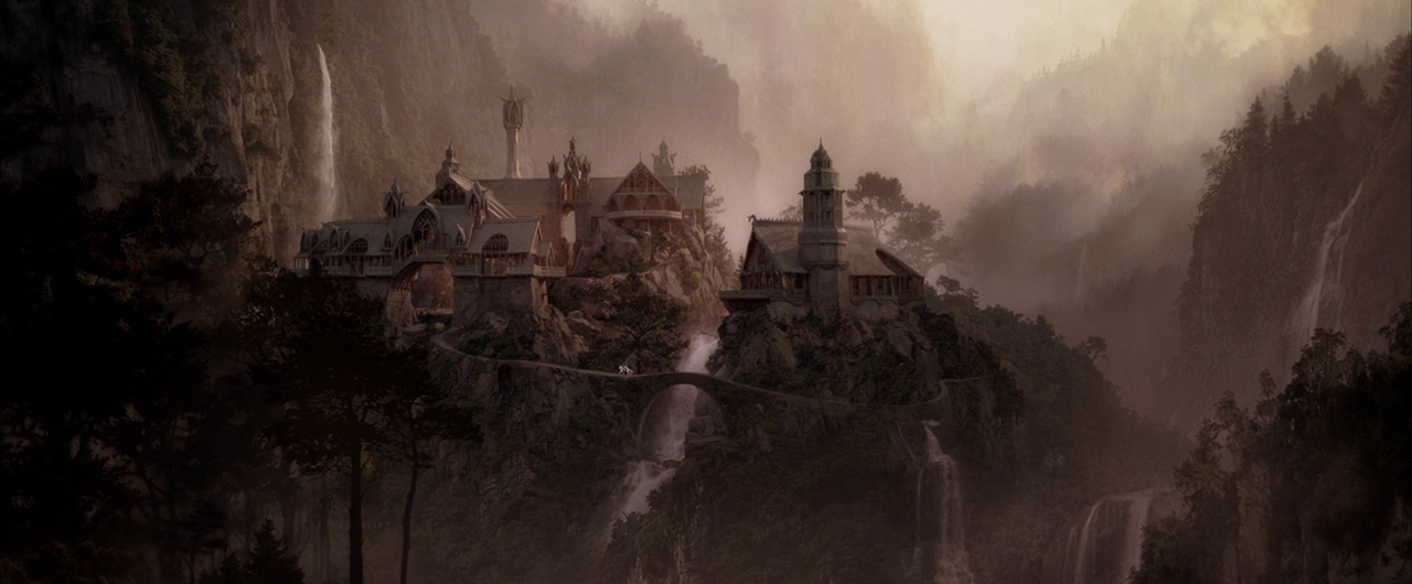 A complex stone city sits atop rocky crags surrounded by waterfalls and lush trees. Thick fog fills the deep valley while stone arches connect the various city structures.
