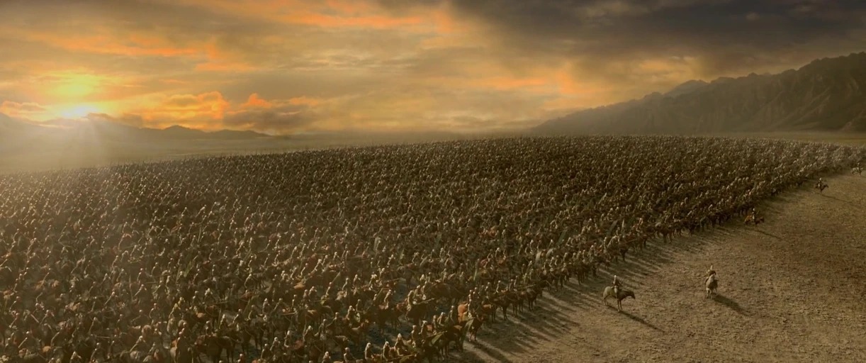 A vast, sprawling army of soldiers on horseback gathers on a flat dusty plain. Mountains rise in the distant background under a cloudy sunset sky.