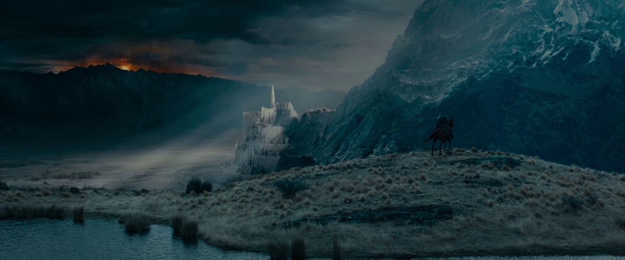 A vast, rugged landscape features a distant white stone castle nestled against dark mountains. A solitary figure on horseback pauses on a grassy hill overlooking the valley.