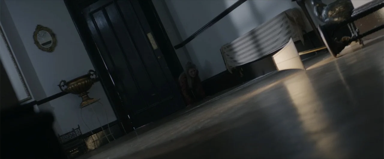 dutch angle shots example from Cinderella's Curse: A dimly lit Victorian-style hallway features a dark door and ornate gilded wall decor. A woman crou