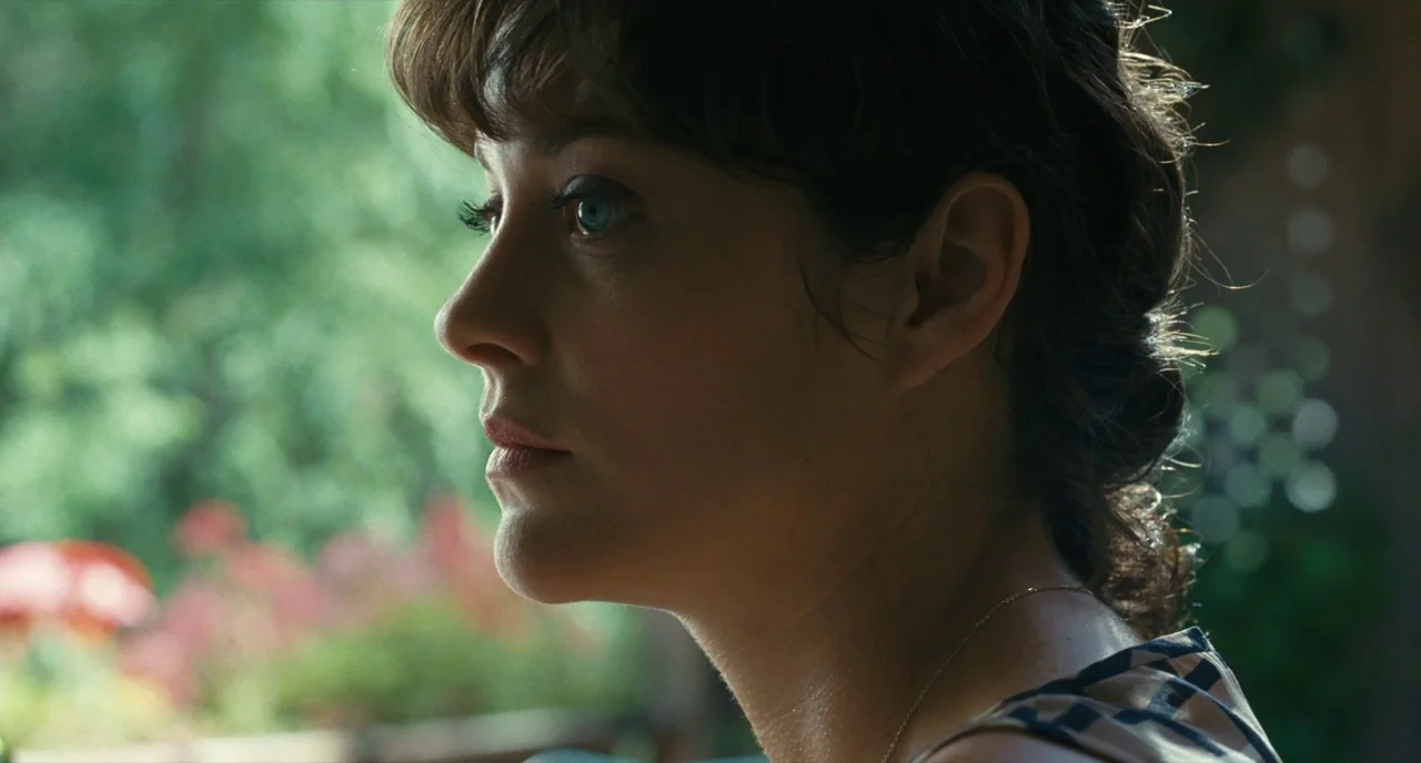 It’s Only The End Of The World (2016) movie still: closeup — A woman stands in profile against an out-of-focus green background of foliage and…