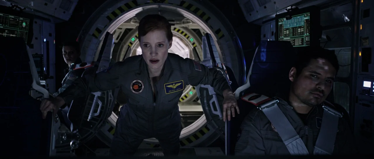 The Martian (2015) movie still: medium — A dark, cramped spacecraft interior features glowing control panels and circular bulkhead portals. Three…