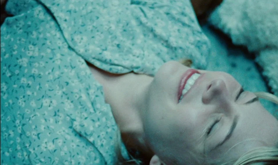 Blue Valentine (2010) movie still: closeup — A close-up view of a person lying on bedding with a floral pattern. The subject is resting with their…