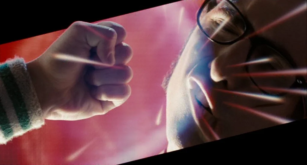 dutch angle shots example from Scott Pilgrim Vs The World: A close-up view shows a clenched fist positioned inches from a man's face. The composition