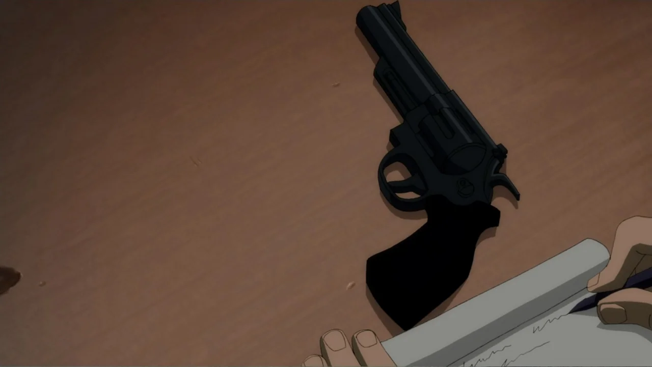 Batman: The Dark Knight Returns, Part 1 (2012) movie still: closeup — A flat wooden desk surface holds a black revolver and a notepad with paper.…