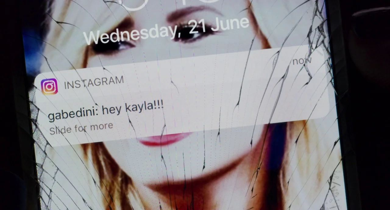 Eighth Grade (2018) movie still: closeup — A cracked smartphone screen displays an Instagram notification message from a user named gabedini. The…