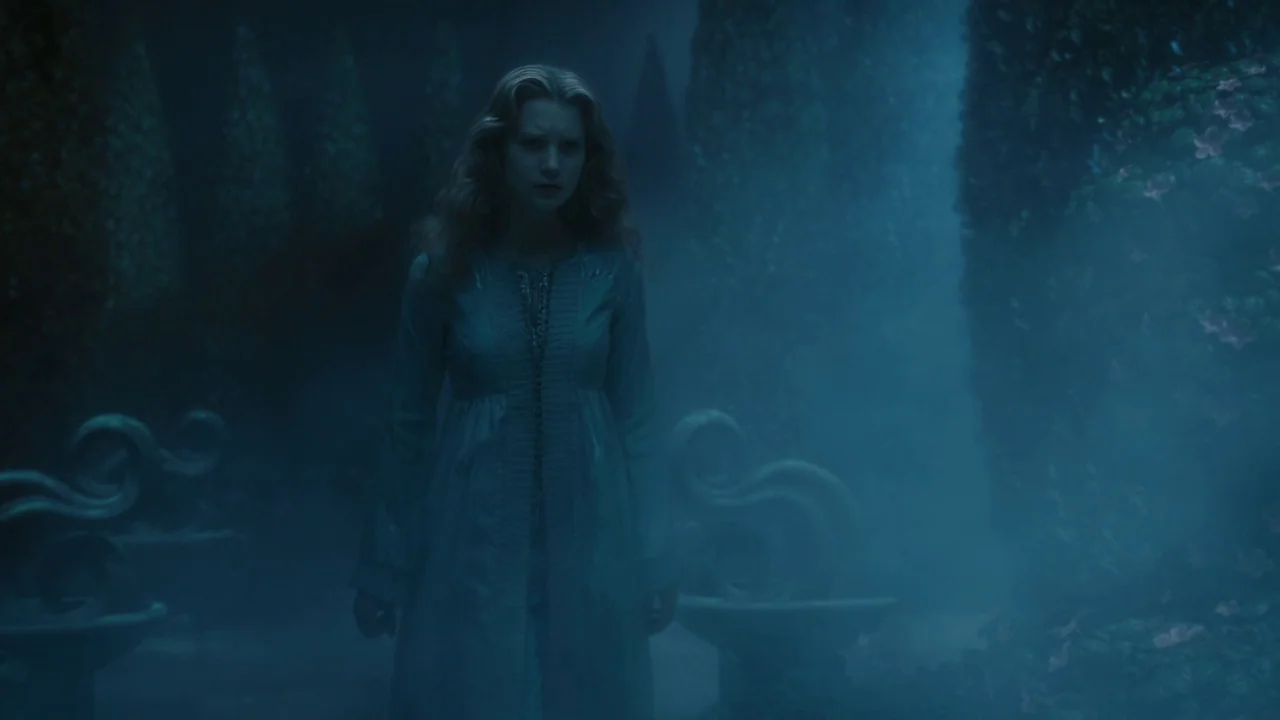 Alice in Wonderland (2010) movie still: medium — A dense hedge maze at night is obscured by thick, swirling blue fog. A young woman stands alone in…
