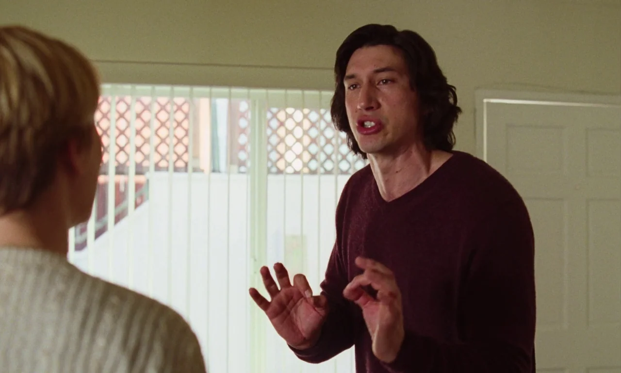 Marriage Story movie still: medium — An interior space features off-white walls and a large, bright window with vertical blinds. A man in a maroon…