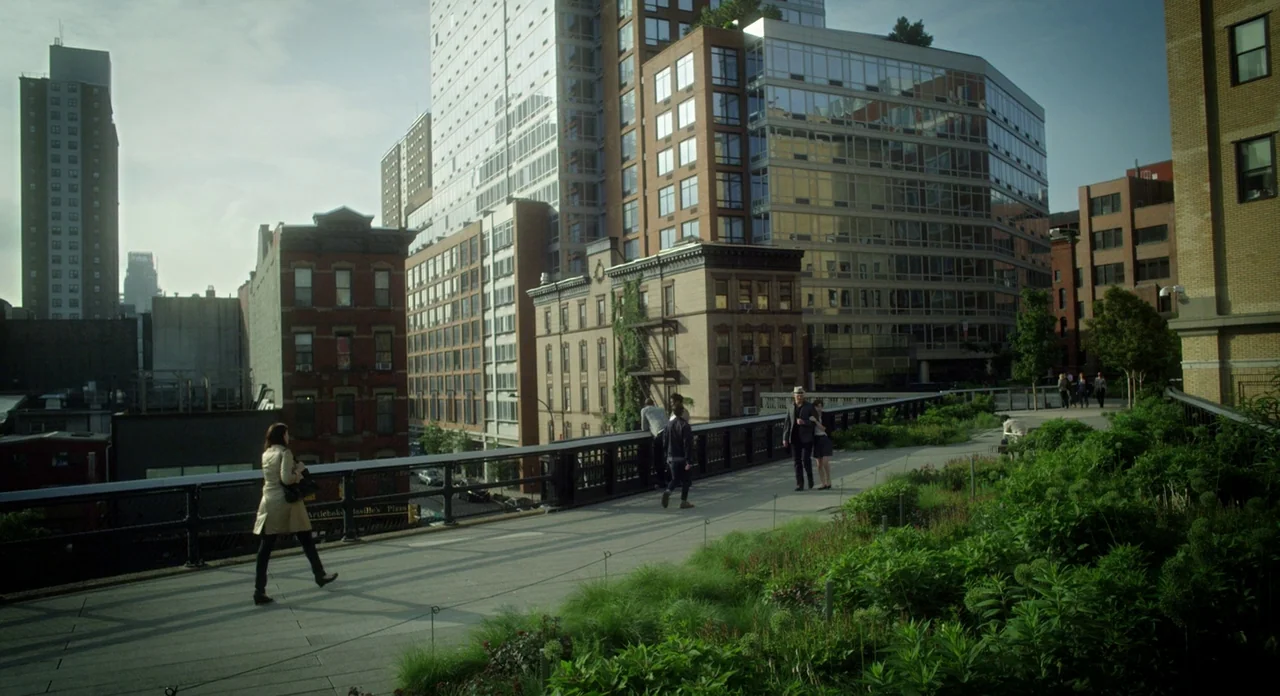 Side Effects (2013) movie still: wide — An elevated linear park winds through a dense urban neighborhood of brick and glass. People stroll along the…