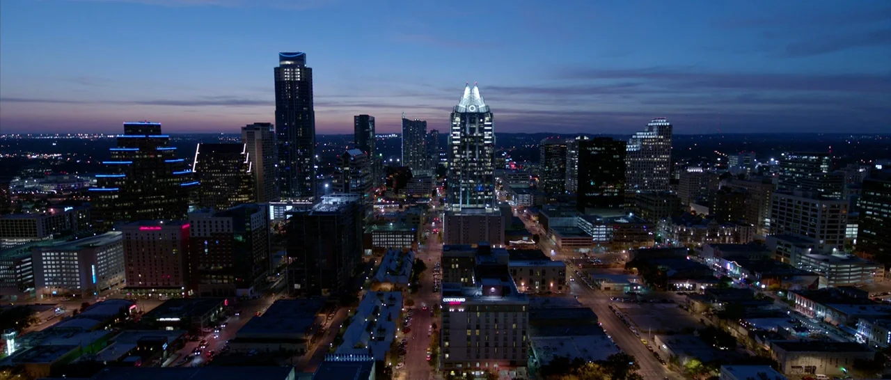 Song to Song (2017) movie still: establishing — An expansive aerial view of the Austin city skyline at dusk. Numerous skyscrapers and illuminated…