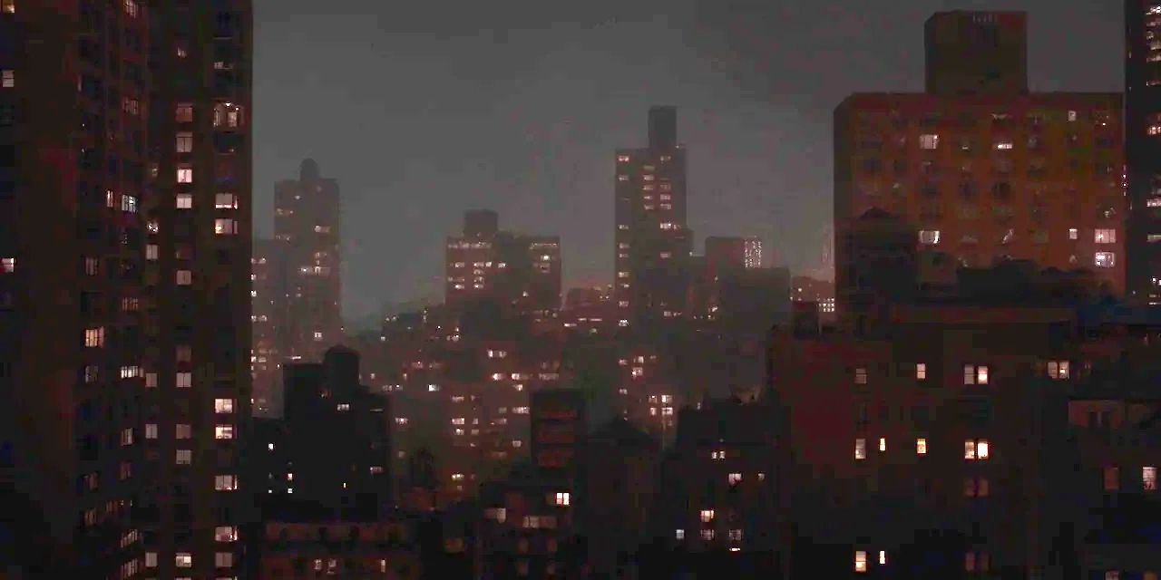 The Sound of Silence movie still: establishing — A dense urban skyline at night features tall apartment buildings silhouetted against a dark sky.…