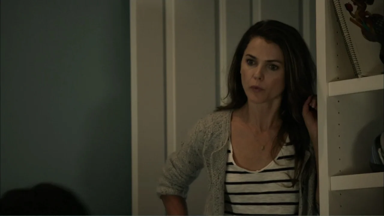 Dark Skies (2013) movie still: medium — A woman stands in the doorway of a room with blue walls and white trim. She leans against the white wooden…