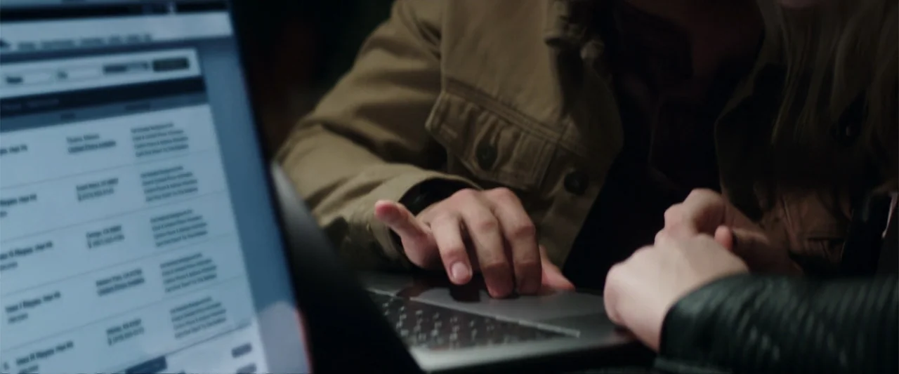 Truth or Dare (2018) movie still: medium — An interior space with a laptop displaying a list of search results. Two people lean toward the screen…