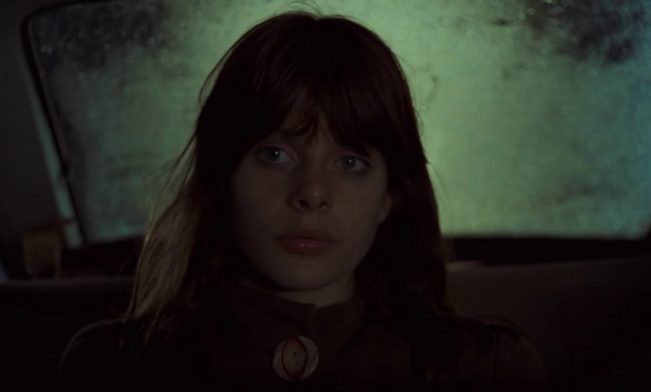 Wrong Move (1975) movie still: closeup — The interior of a car at night with a blurred rain-streaked window behind. A young woman sits in the…