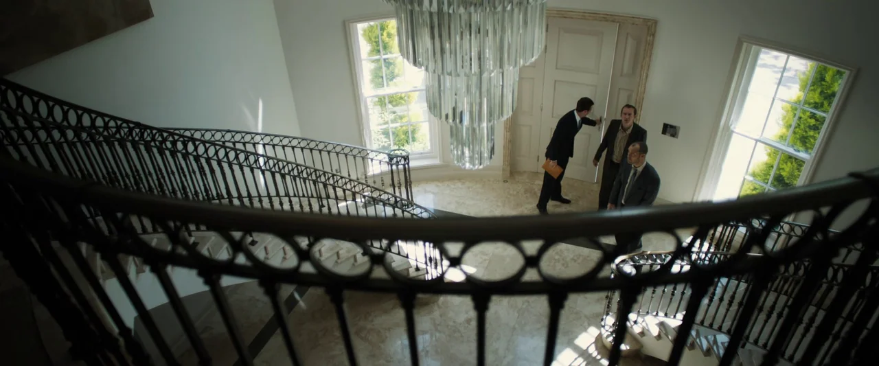 Black Sea (2014) movie still: wide — A spacious foyer features marble floors, large white double doors, and a grand staircase. Three men in formal…