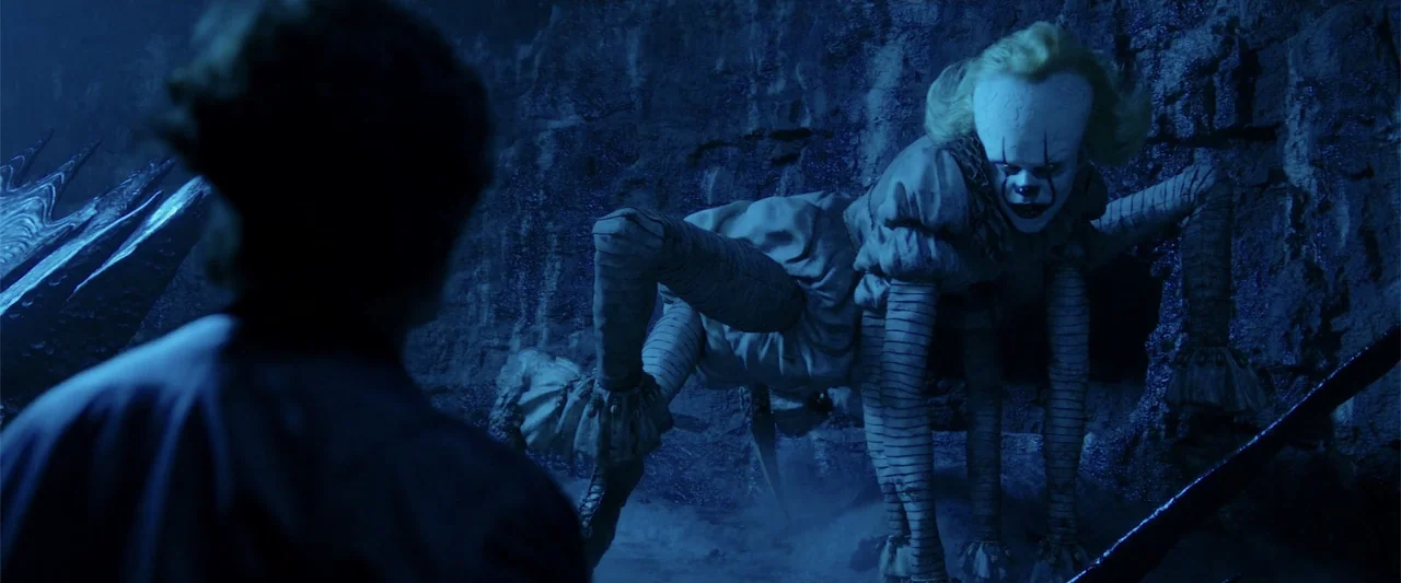 K.G.F: Chapter 2 (2022) movie still: medium — A dark rocky cavern with uneven stone walls serves as the backdrop. A monstrous spider-clown crawls…