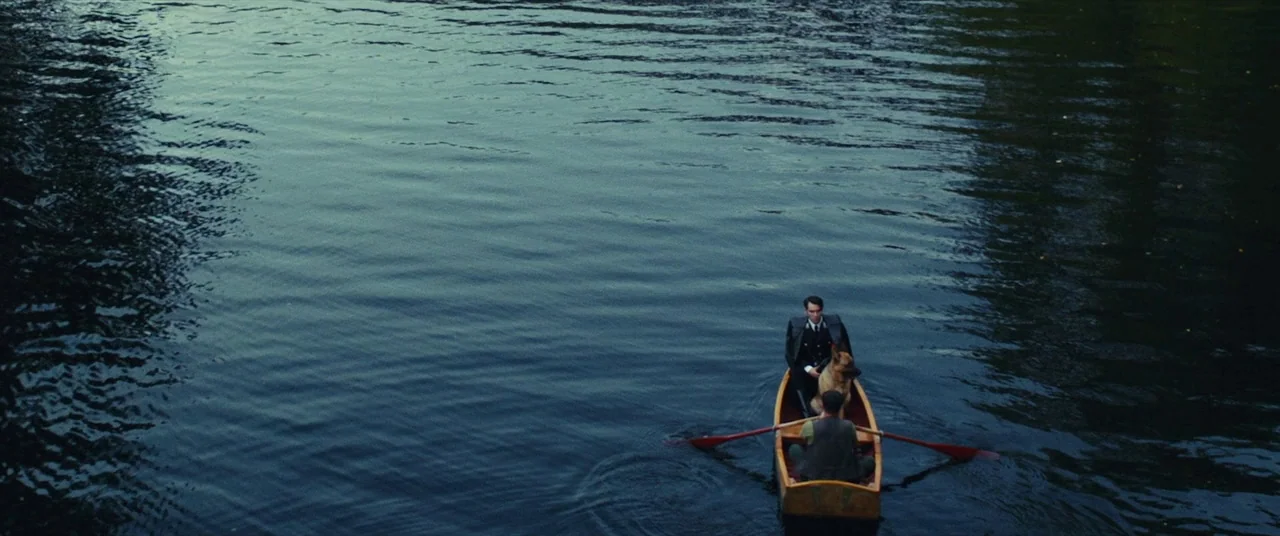 The Man Who Killed Hitler and Then the Bigfoot (2018) movie still: wide — A wooden rowboat floats on a dark, calm body of water. Two men sit in the…