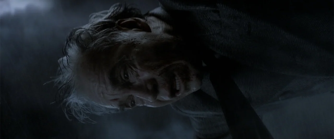 dutch angle shots example from Fantastic Beasts: The Crimes of Grindelwald: A rain-swept urban exterior environment is shown in a sharp, tilted Dutch