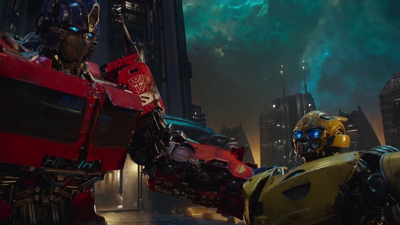 Bumblebee (2018) movie still: medium — A dark alien landscape features sharp metallic towers under a glowing teal nebula. Optimus Prime and…