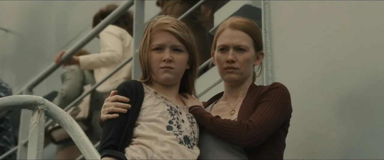 World War Z (2013) movie still: medium — A woman and a young girl stand on the deck of a ship. The woman puts a protective hand on the girl's…