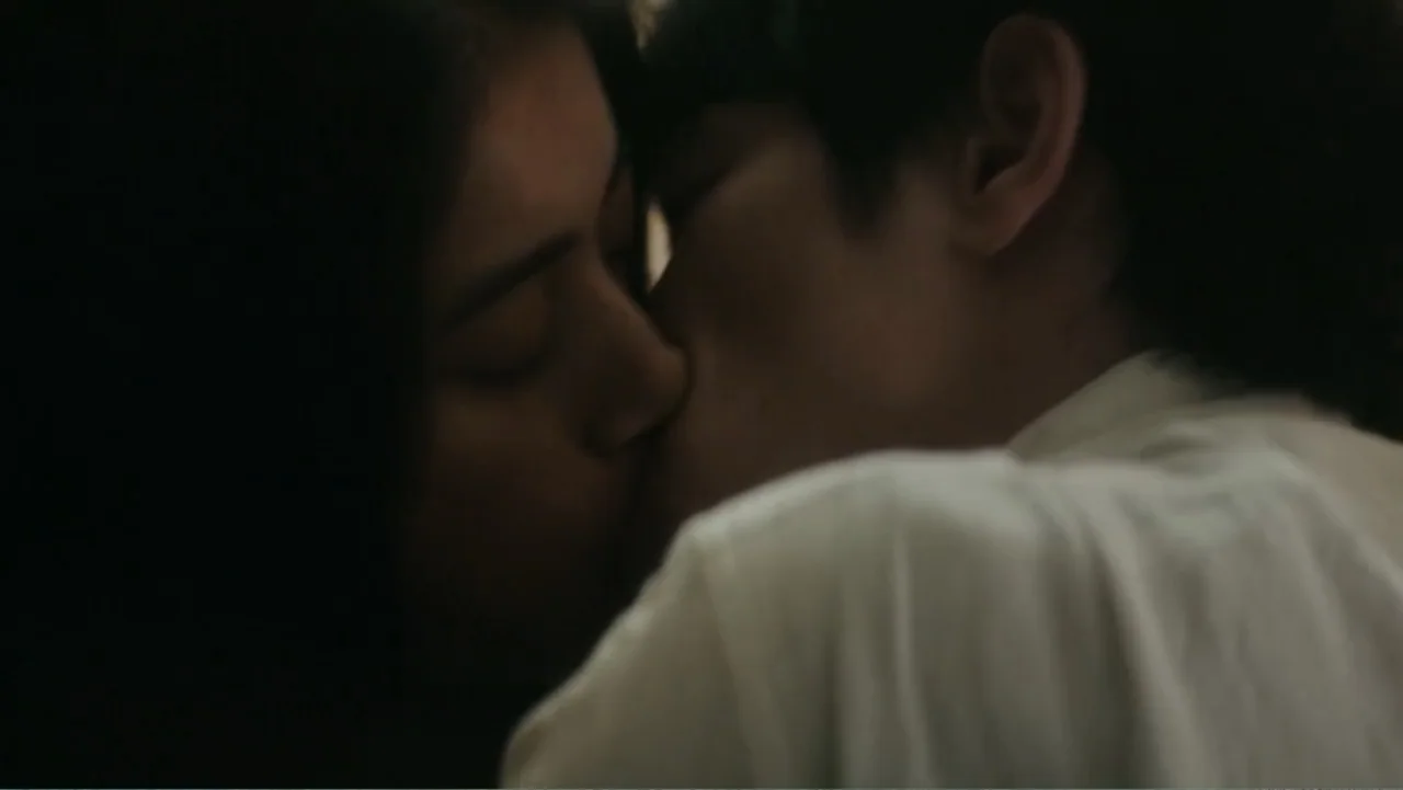 Bel Canto (2018) movie still: closeup — A dimly lit indoor space with shadows obscuring the background. Two individuals with their eyes closed are…