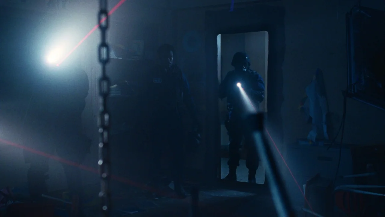 Saw III (2006) movie still: medium — A dark, smoke-filled room is illuminated only by weapon-mounted flashlights and red laser beams. Two tactical…