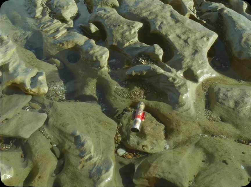 Jauja (2014) movie still: closeup — A miniature nutcracker figurine rests in a shallow water-filled pocket of coastal rock. The surrounding…