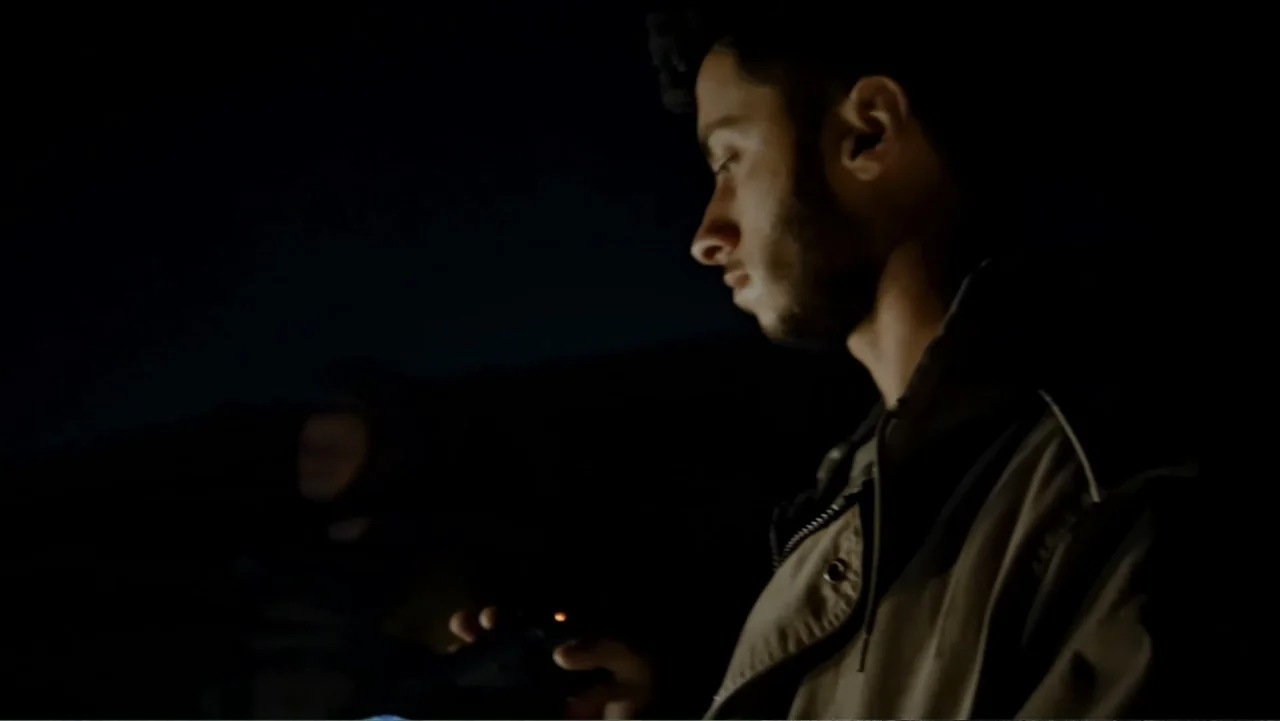 No Other Land (2024) movie still: medium — A dark outdoor setting at night with no visible architectural details behind the subject. A young man…