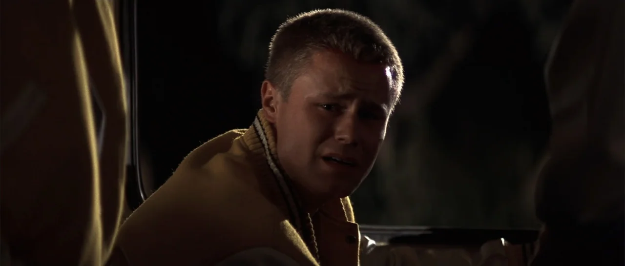 Jeepers Creepers 2 (2003) movie still: closeup — A dark vehicle interior features a young man in a varsity jacket. He looks toward the side of the…