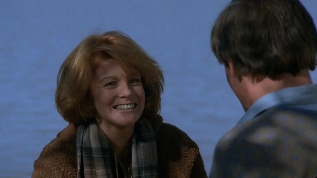 Magic (1978) movie still: medium — A person stands before a large body of water during the daytime. A woman with auburn hair smiles warmly at a man…