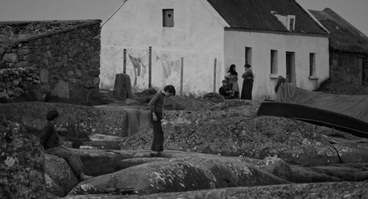 Song of Granite (2017) movie still: wide — A remote village features whitewashed stone cottages situated among rugged and craggy coastal rock…