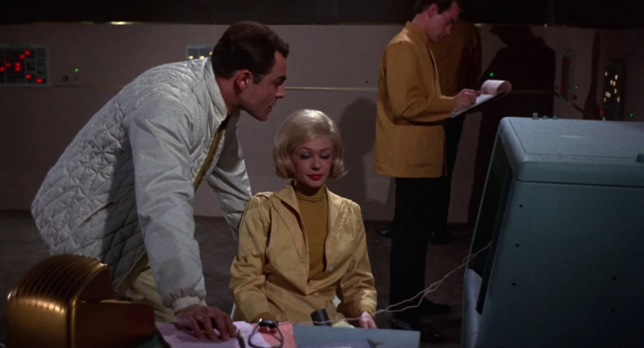 Queen of Blood (1966) movie still: medium — A retro-futuristic control room features consoles with illuminated buttons and clean, beige-paneled…