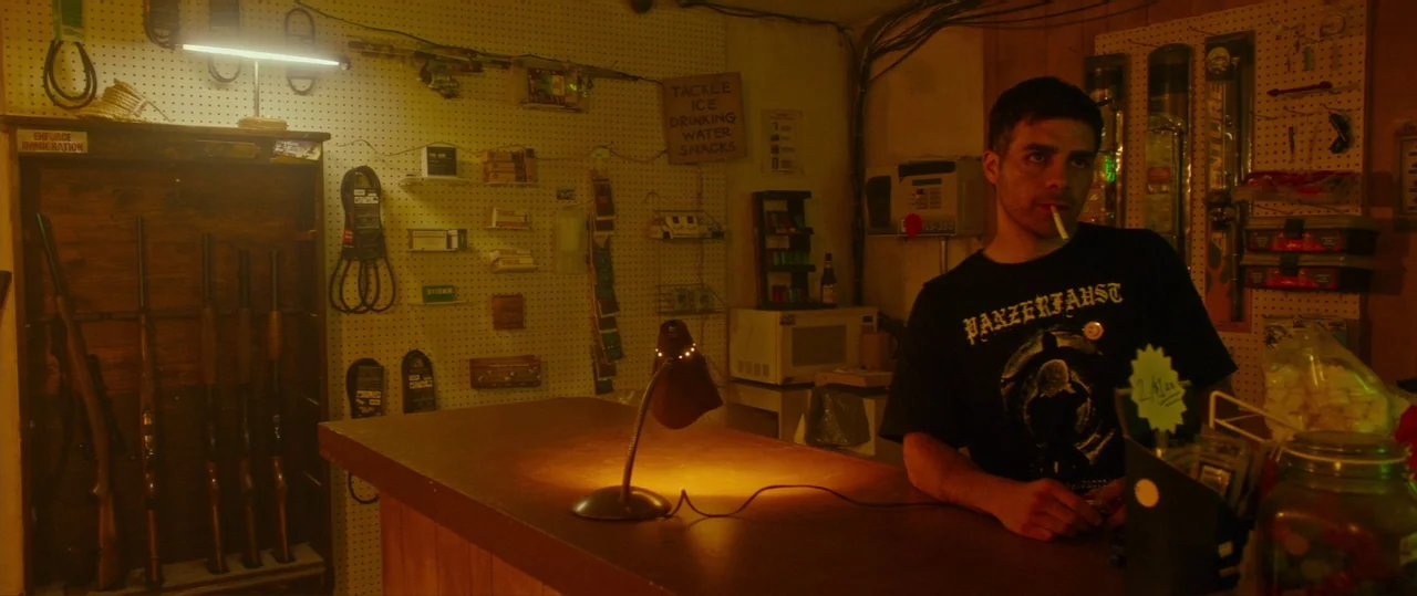 Random Acts of Violence (2019) movie still: medium — A dimly lit convenience store features pegboard walls covered in retail merchandise and…