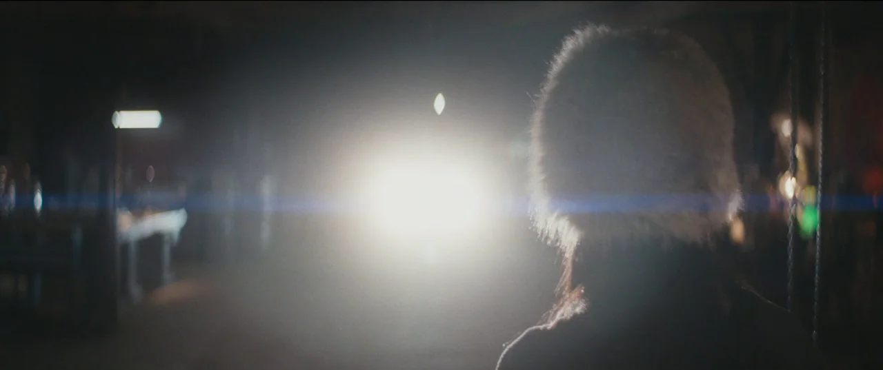 Humanist Vampire Seeking Consenting Suicidal Person (2023) movie still: medium — A dark space features a bright light source illuminating the scene…