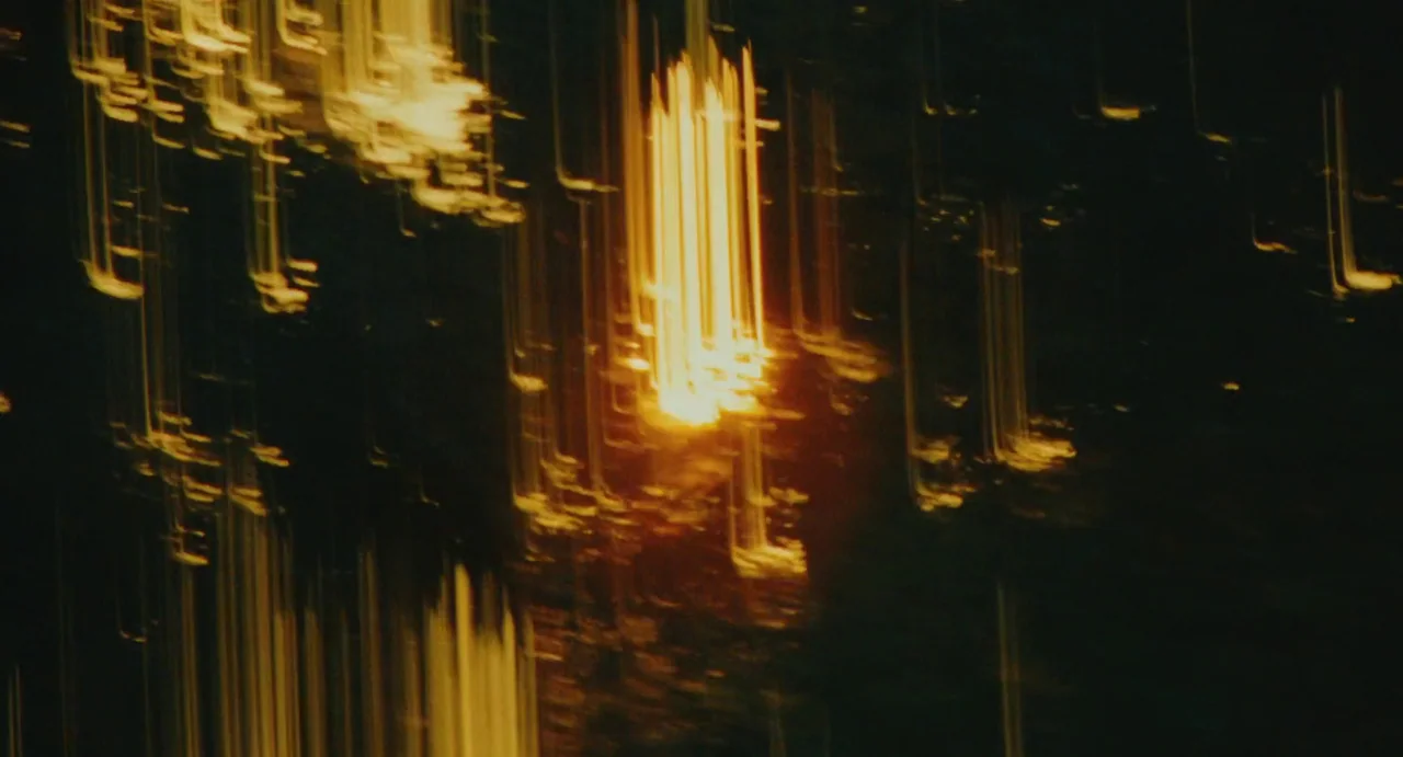 The Giant (2019) movie still: establishing — A dark night setting featuring vertical motion-blurred streaks of bright golden light. These light…