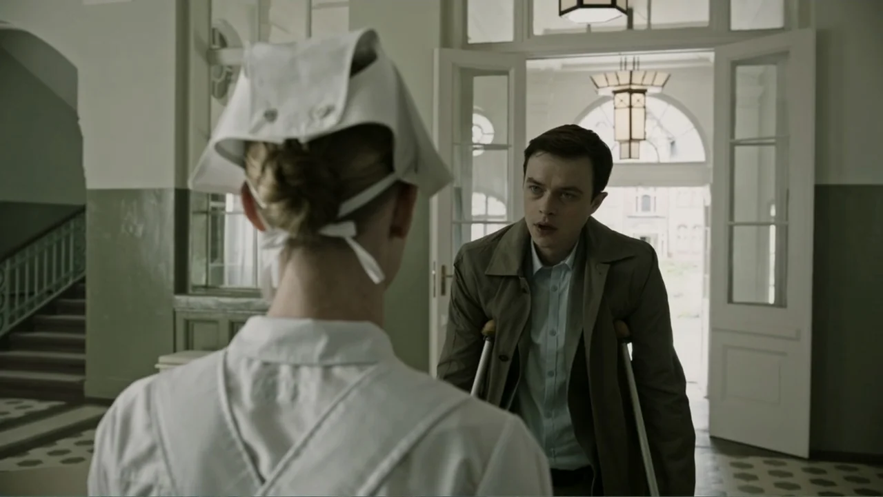 A Cure for Wellness (2017) movie still: medium — A sterile, high-ceilinged building interior features white double doors and tiled flooring. A young…