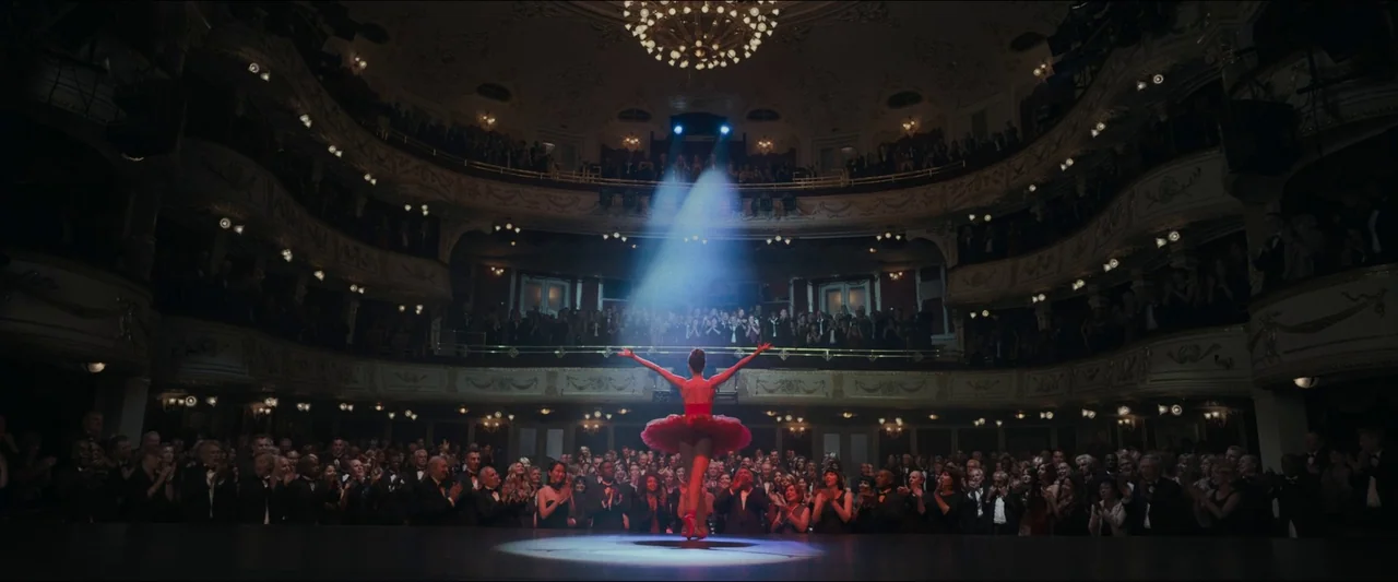 Birds of Paradise (2021) movie still: wide — A grand, multi-tiered historic opera house is packed with a large audience in formal attire. A lone…
