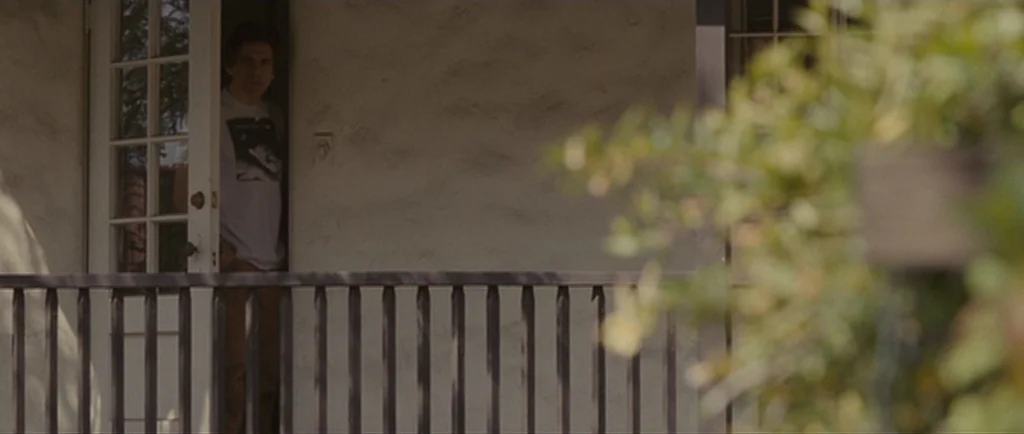 Greenberg (2010) movie still: medium — A man stands in the threshold of an exterior doorway on a porch. The scene is shot from a distance with…