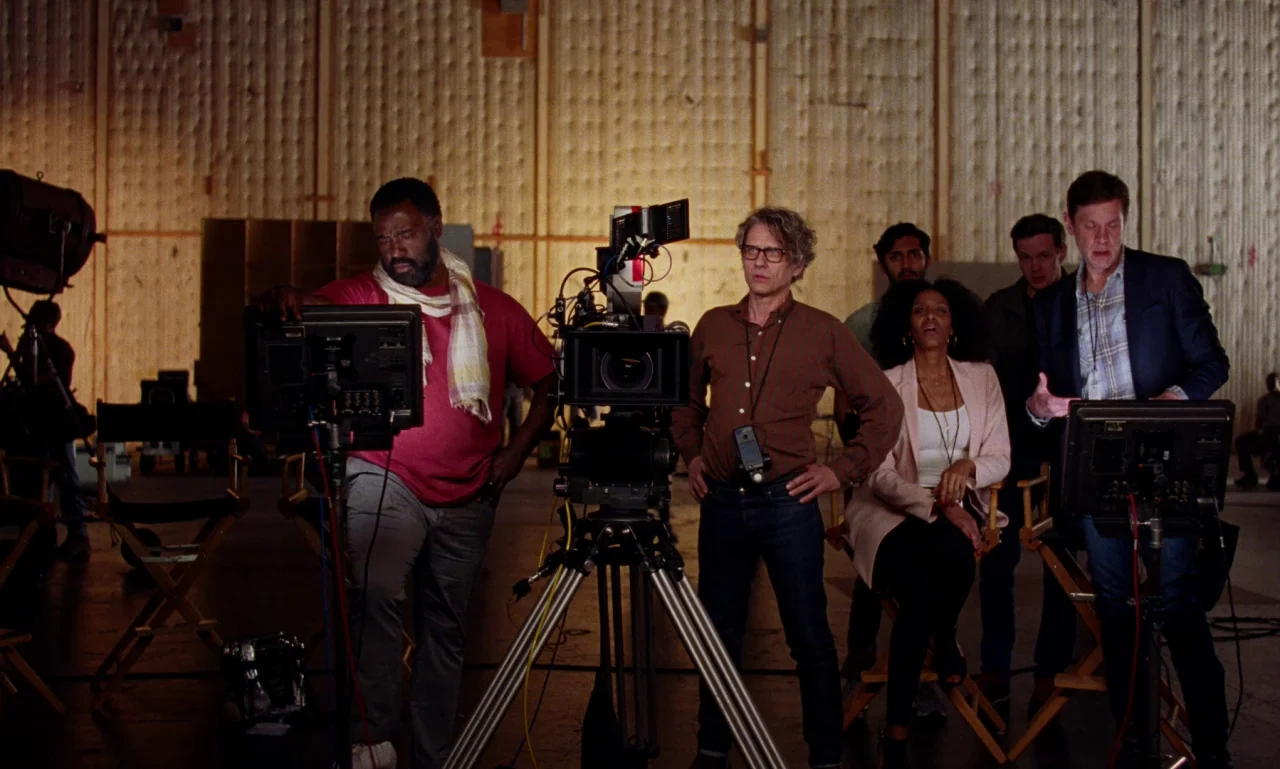 Marriage Story movie still: wide — A spacious film production studio features sound-dampening wall panels and professional camera equipment. A group…