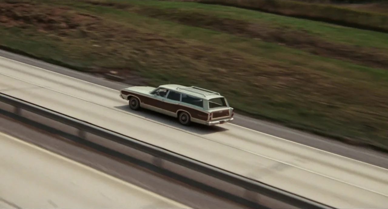 The Rain People (1969) movie still: wide — A light-colored station wagon with wood-grain side panels drives along a wide concrete highway. The…