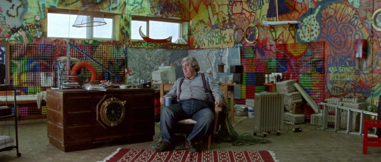 Arabian Nights: Volume 1 – The Restless One (2015) movie still: wide — A cluttered office features walls covered in colorful graffiti and layers of…