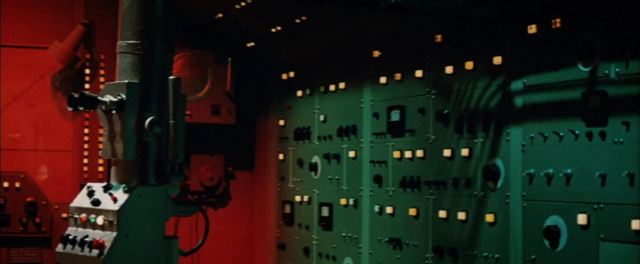 Destroy All Monsters (1968) movie still: establishing — A dimly lit submarine command deck features complex electronic control panels and technical…