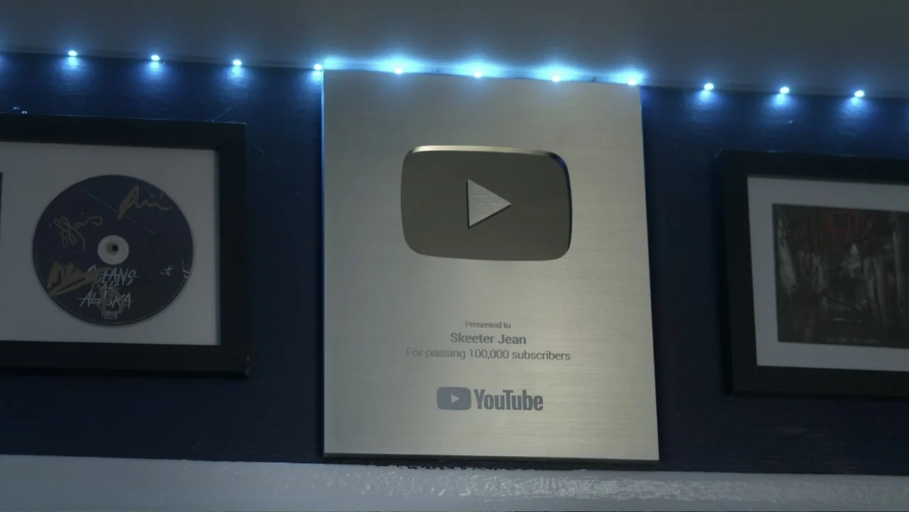 Predators (2010) movie still: medium — A metallic YouTube creator award plaque is centered on a dark blue wall surface. The plaque is flanked by…