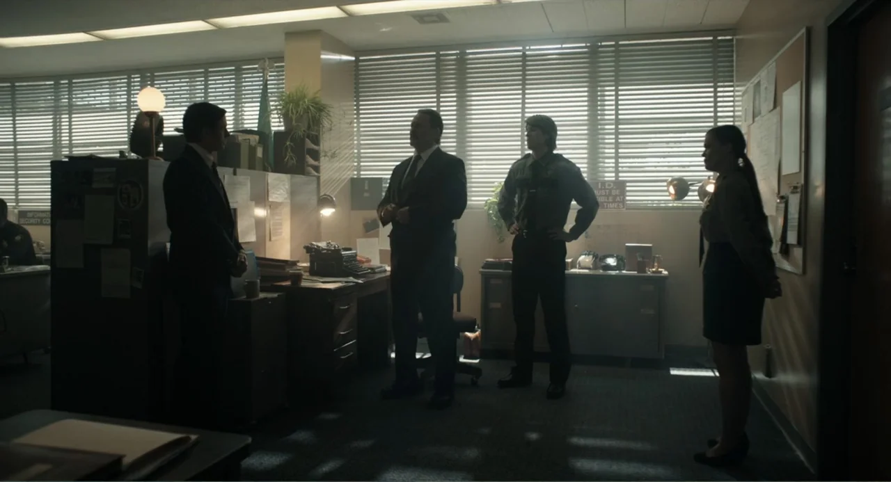 Ted Bundy: American Boogeyman (2021) movie still: fullbody — A cluttered 1980s administrative office features rows of cubicles and large blinds over…