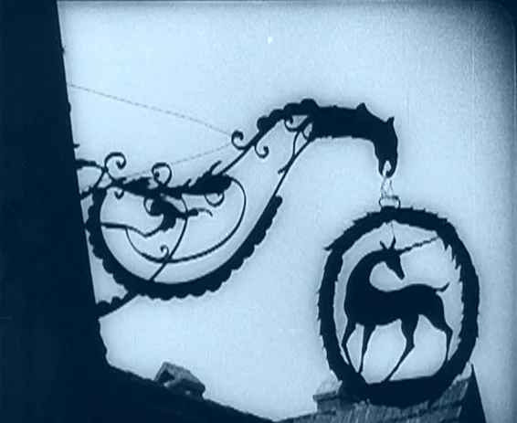 Destiny (1921) movie still: medium — A metal inn sign shaped like a unicorn hangs from a wrought iron bracket. The structure is silhouetted against…