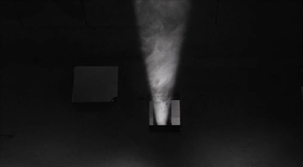The Last Picture Show (1971) movie still: establishing — A dark space features a single light beam pointing upward from a floor level vent. Thick…