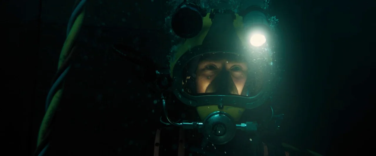 Black Sea (2014) movie still: closeup — A deep-sea environment is pitch black, with only small air bubbles floating in suspension. A diver in a…