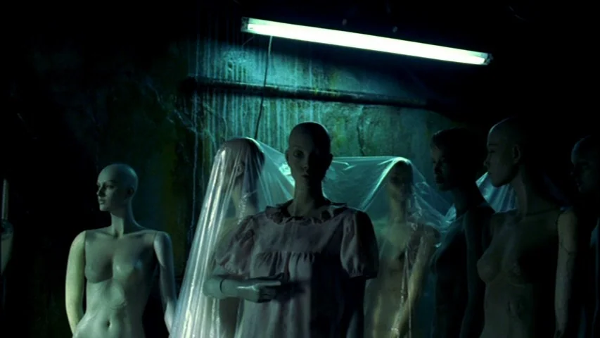 Save The Green Planet! (2003) movie still: medium — Several mannequins stand in a dark, grimy storage area with water-stained concrete walls. One…