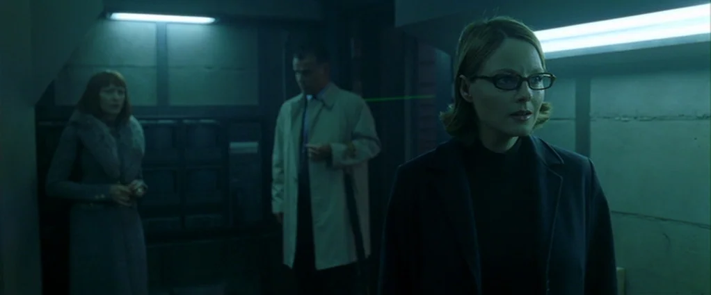 Panic Room (2002) movie still: medium — A dark command center features industrial concrete walls and banks of electronic equipment monitors. Three…
